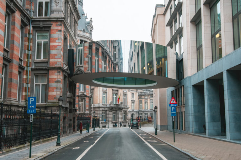 ベルギー・ブリュッセル中心部に実在する円形の歩道橋「Tondo」。歴史的な街並みとモダンな循環型デザインの融合を象徴する風景。